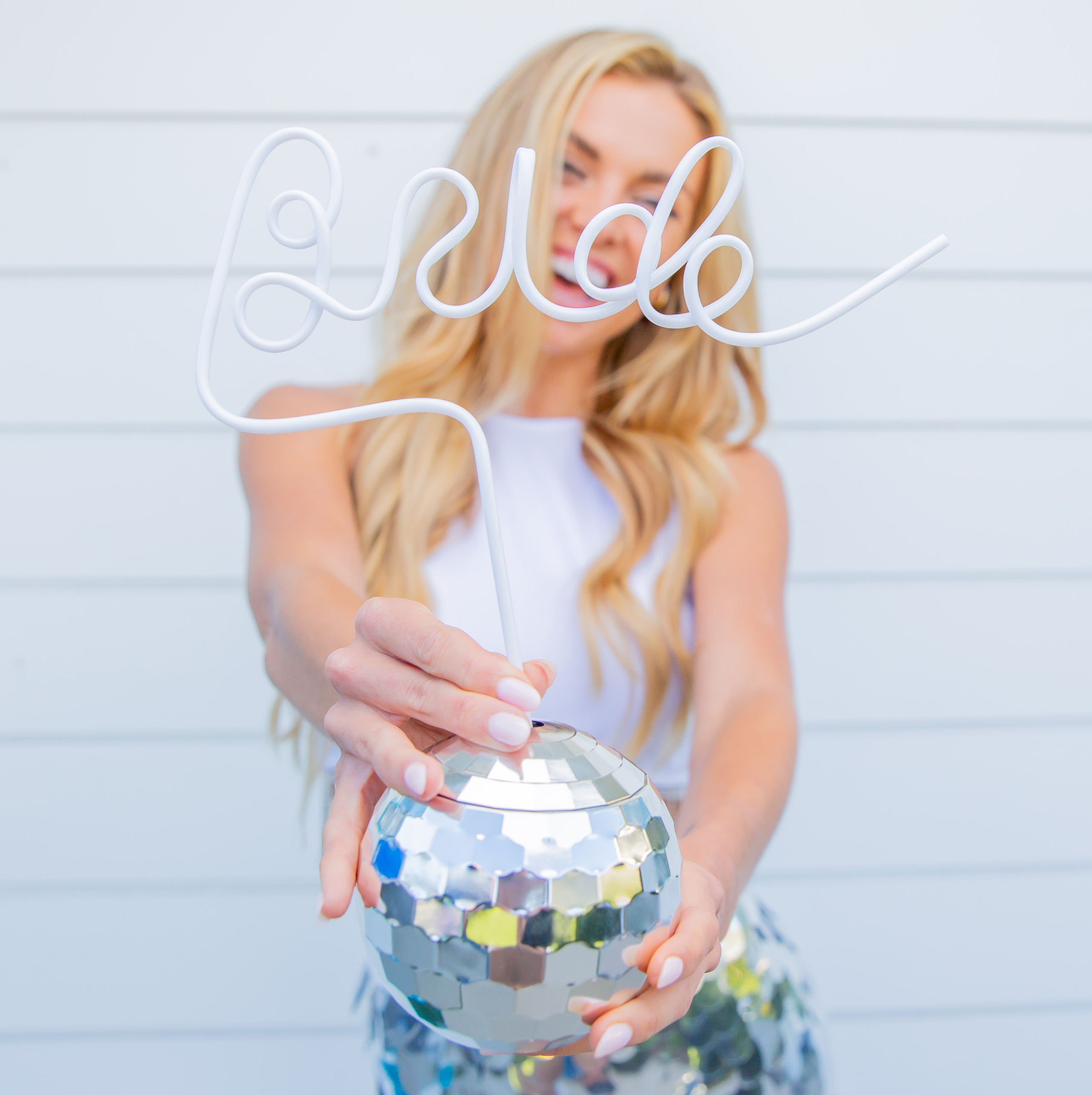 Bride at a disco bachelorette party holding a sparkling disco ball tumbler with a white 'Bride' straw—fun, photo-ready party favor drinkware.