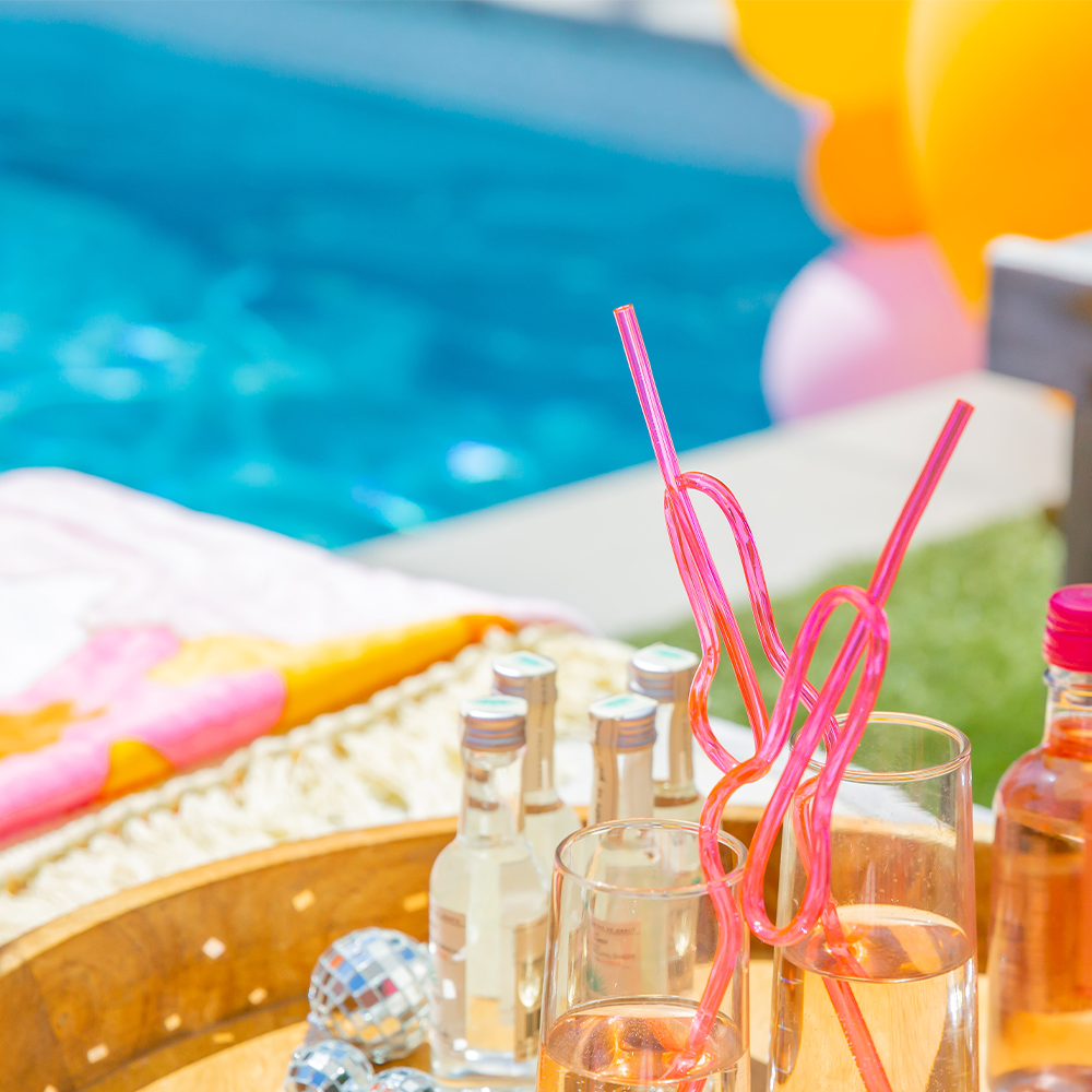 Bachelorette pool party table with drinks, Sunkissed Party Co. party decorations, and accessories.